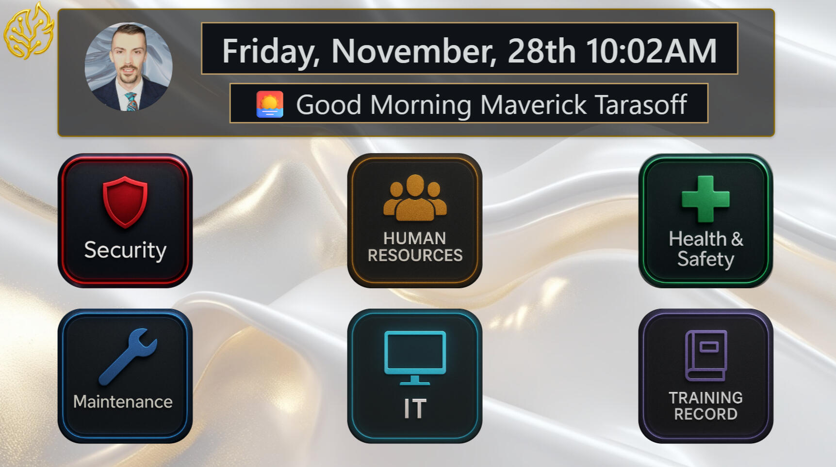 A polished dashboard interface on a silver fabric-like background. It shows a profile photo, the date and time, a greeting to Maverick Tarasoff, and six large tiles labeled Security, Human Resources, Health & Safety, Maintenance, IT, and Training Record.